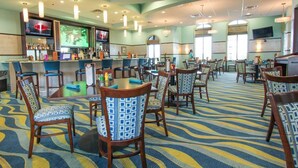 A hotel lobby with a bar area, multiple dining tables, and chairs. - Villa in Champions Gate Resort 1010 (Davenport)
