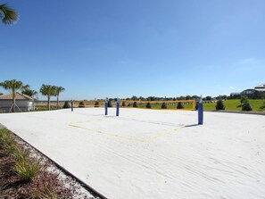 Un terrain de sport avec un filet, des poteaux bleus et des lignes de démarcation jaunes.