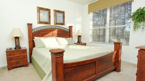 A bedroom with a wooden bed, a nightstand, a dresser, and two framed pictures on the wall. - Villa in Windsor Hills Resort 1701 (Kissimmee)