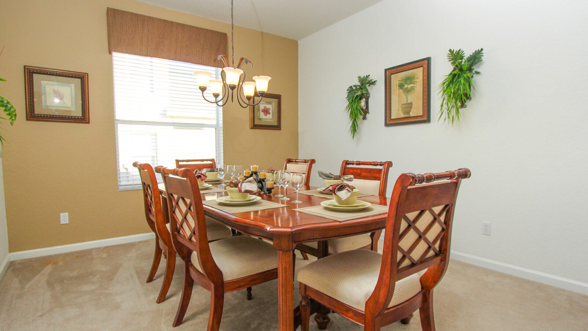 A dining room with a wooden table set for six, surrounded by six chairs.