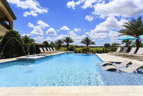 A swimming pool with lounge chairs and a water feature.