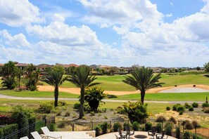 A residential area with a golf course, palm trees, and houses in the background.
