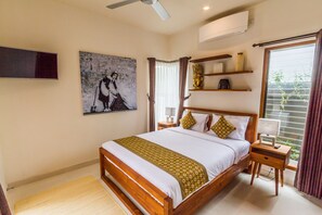 A bedroom with a wooden bed, a painting, a ceiling fan, and a window with curtains.