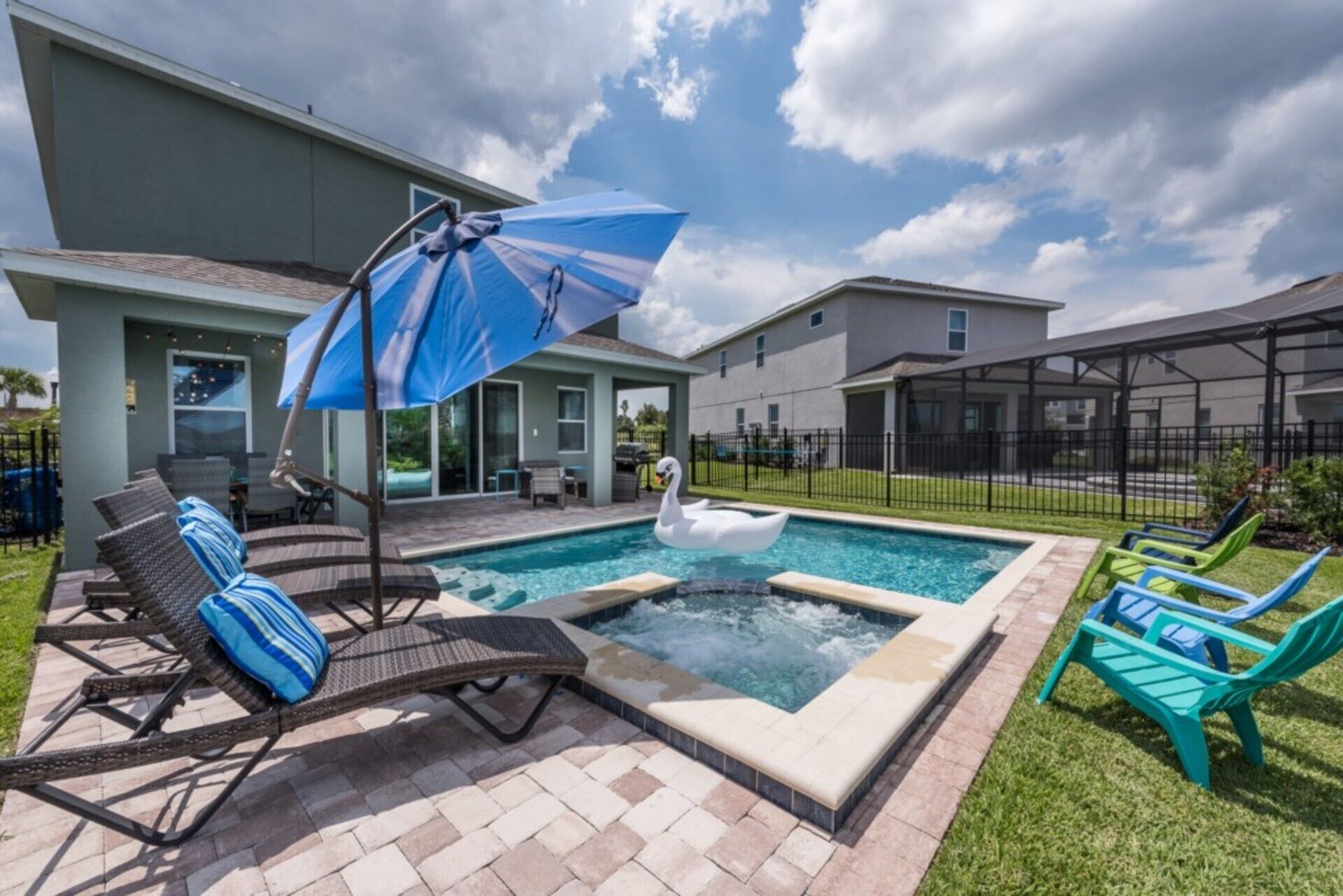 Une piscine avec un flotteur en forme de cygne, des chaises longues et un espace patio couvert.