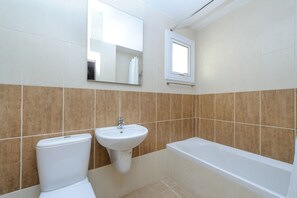 A bathroom with a toilet, sink, and bathtub.
