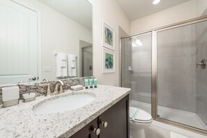 A bathroom with a marble sink, a toilet, and a glass-enclosed shower. - Villa in Encore Resort at Reunion 1998 (Kissimmee)