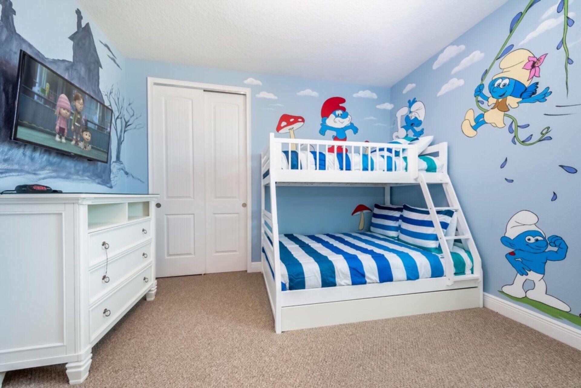 A bunk bed with blue and white bedding, a white dresser with drawers, and a door.