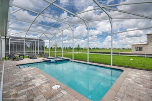 A covered swimming pool with a view of a grassy field and a distant building. - Villa in Champions Gate Resort 2528 (Davenport)