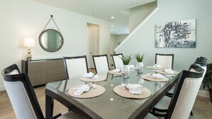 Comedor con una mesa de vidrio, sillas y un cuadro en la pared.