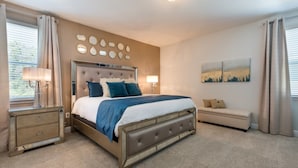 A bedroom with a large bed, bedside tables, a bench, and artwork on the walls. - Villa in Encore Resort at Reunion 2986 (Kissimmee)