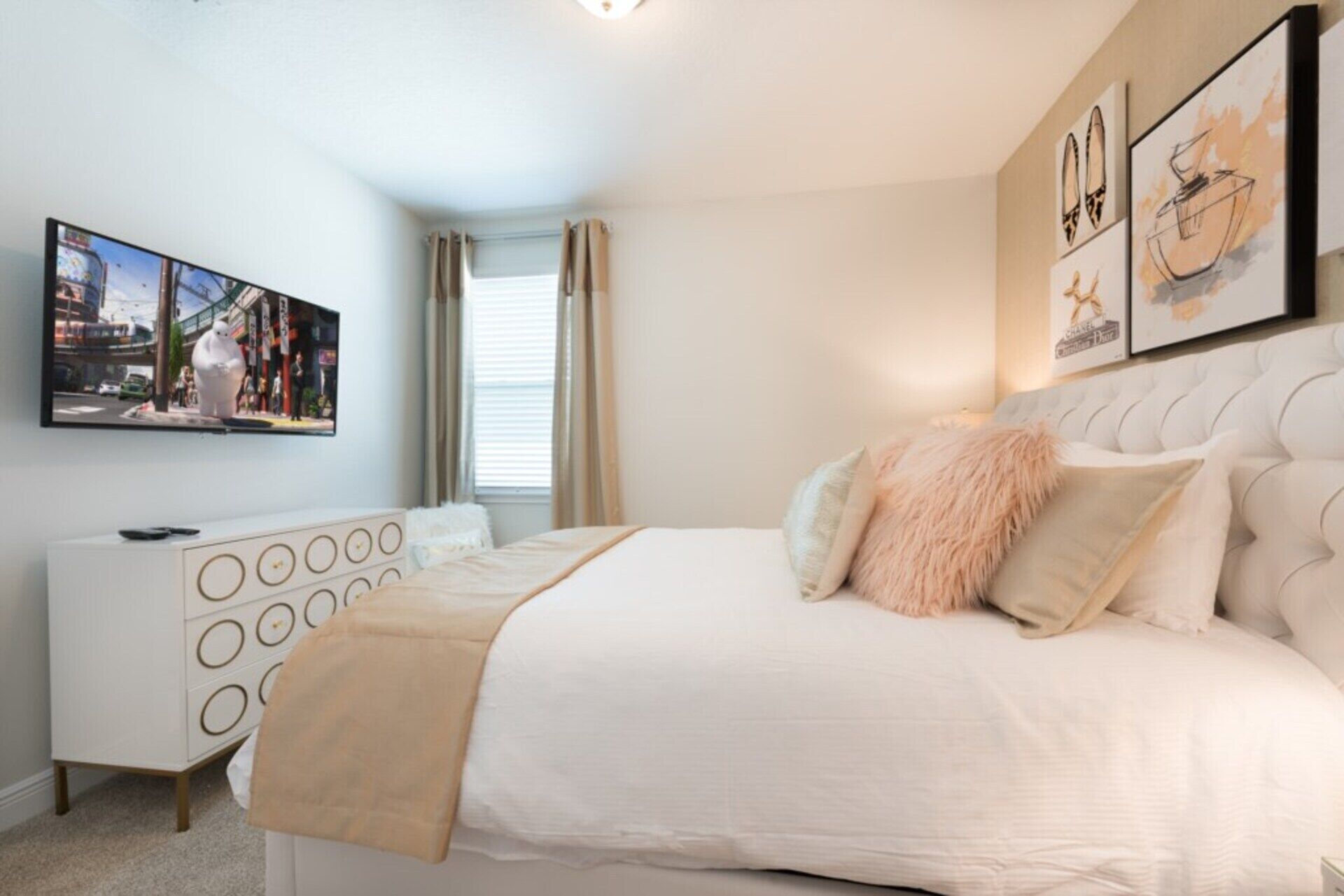 A bedroom with a large bed, a white dresser, a painting on the wall, and a window with curtains.
