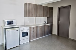 A compact kitchen with a microwave, oven, and sink.