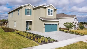 A two-story residential building with a garage, a front lawn, and a clear sky. - Villa in Encore Resort at Reunion 1995 (Kissimmee)
