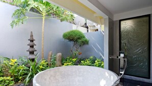 A modern bathroom with a large bathtub, a small zen garden, and a decorative wall. - Private Villa in Seminyak 1142 (Seminyak)