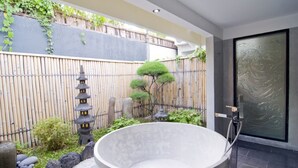 A modern bathroom with a large bathtub, a small garden area with a bamboo fence, and a traditional Japanese lantern. - Private Villa in Seminyak 1142 (Seminyak)