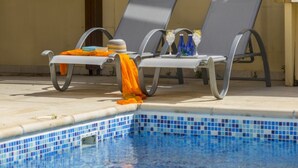A poolside area with lounge chairs and a tiled pool. - Beautiful Villa With Private Pool, Protaras Villa 1010 (Paralimni)