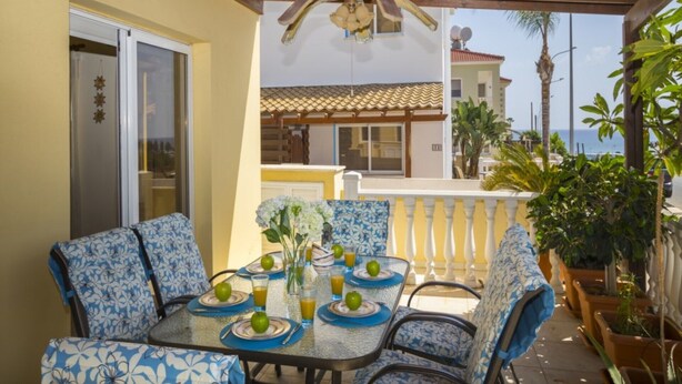 A covered patio with a table set for two, featuring blue patterned chairs and a glass table. - Beautiful Villa With Private Pool, Protaras Villa 1010 (Paralimni)