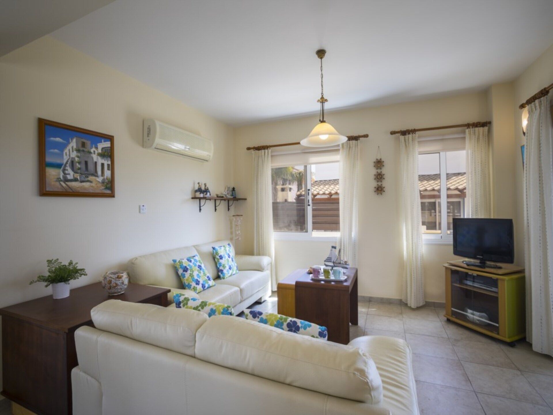 Una sala de estar con un sofá, una mesa de centro, un mueble para televisión y un cuadro en la pared.