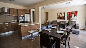 Una cocina moderna con una isla central, un comedor con mesa y sillas, y una sala de estar con sofá y una obra de arte en la pared.