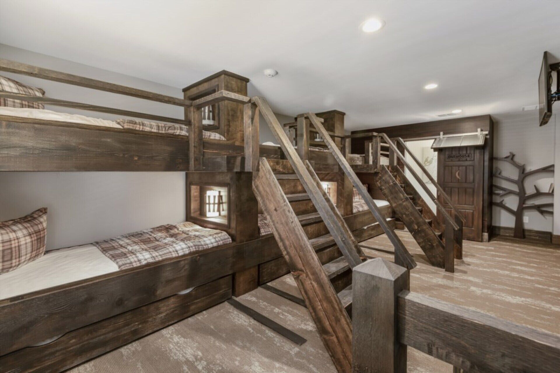 A rustic room with a bunk bed, a wooden staircase, and a small window.