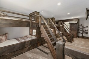 A rustic room with a bunk bed, a wooden staircase, and a small window.