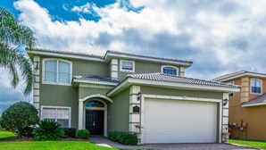 A two-story house with a large garage, a front entrance with a black door, and a well-maintained lawn. - Orlando Villa for Rent With Gorgeous Pool, Vistapark Resort, Villa Orlando 1478 (Davenport)