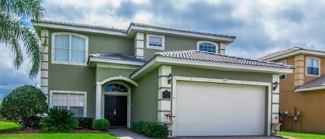 A two-story house with a large garage, a front entrance with a black door, and a well-maintained lawn.