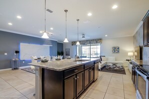 A modern kitchen with a central island, pendant lighting, and a view to the living area. - Villa in Windsor at Westside Resort 2799 (Kissimmee)
