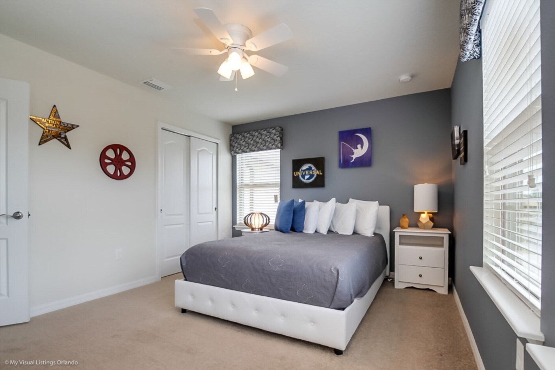 A bedroom with a bed, a nightstand, a lamp, and a ceiling fan.