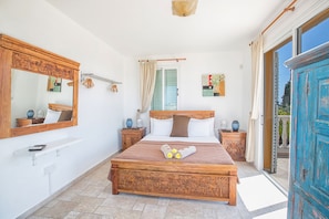 A bedroom with a wooden bed, a large mirror, a bedside table, and a view through a glass door.