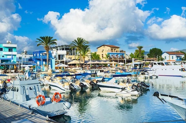 A marina with boats docked, surrounded by buildings with balconies and outdoor seating.