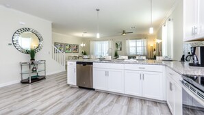 A modern kitchen with white cabinets, a granite countertop, and a central island. - Villa in Champions Gate Resort 1751 (Davenport)