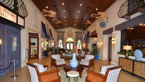 A spacious lobby with a high ceiling, a central seating area with patterned chairs, a large vase, and a reception desk. - Townhome in Champions Gate Resort 2819 (Kissimmee)