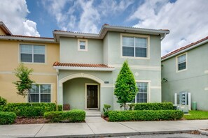 A two-story townhouse with a front entrance, a small porch, and a well-maintained front yard. - Townhome in Champions Gate Resort 2819 (Kissimmee)