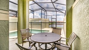 A covered patio area with a pool, outdoor seating, and a view of the sky and water. - Townhome in Champions Gate Resort 2819 (Kissimmee)