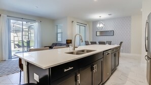 A modern kitchen with a large island, built-in appliances, and a dining area with a chandelier. - Townhome in Champions Gate Resort 2544 (Davenport)