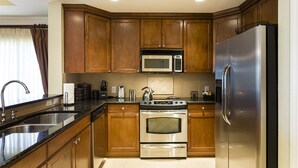 Una cocina moderna con gabinetes de madera, electrodomésticos de acero inoxidable, un horno doble y un microondas.