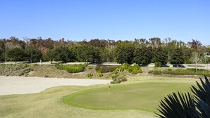 Un campo de golf con búnkeres de arena, un putting green y un mástil con bandera.