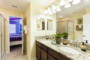 A bathroom with a double sink vanity, a large mirror, and a shower area. - Villa in Champions Gate Resort 1136 (Davenport)