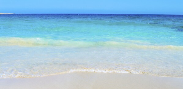 Una spiaggia con acque cristalline color turchese e una battigia sabbiosa.