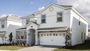 Une maison à deux étages avec un garage, des éléments décoratifs en pierre et une pelouse bien entretenue.