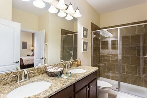 A bathroom with two sinks, a large mirror, and a shower area.