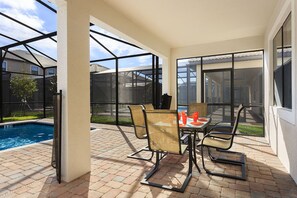 A covered patio with a pool, outdoor seating, and large windows.