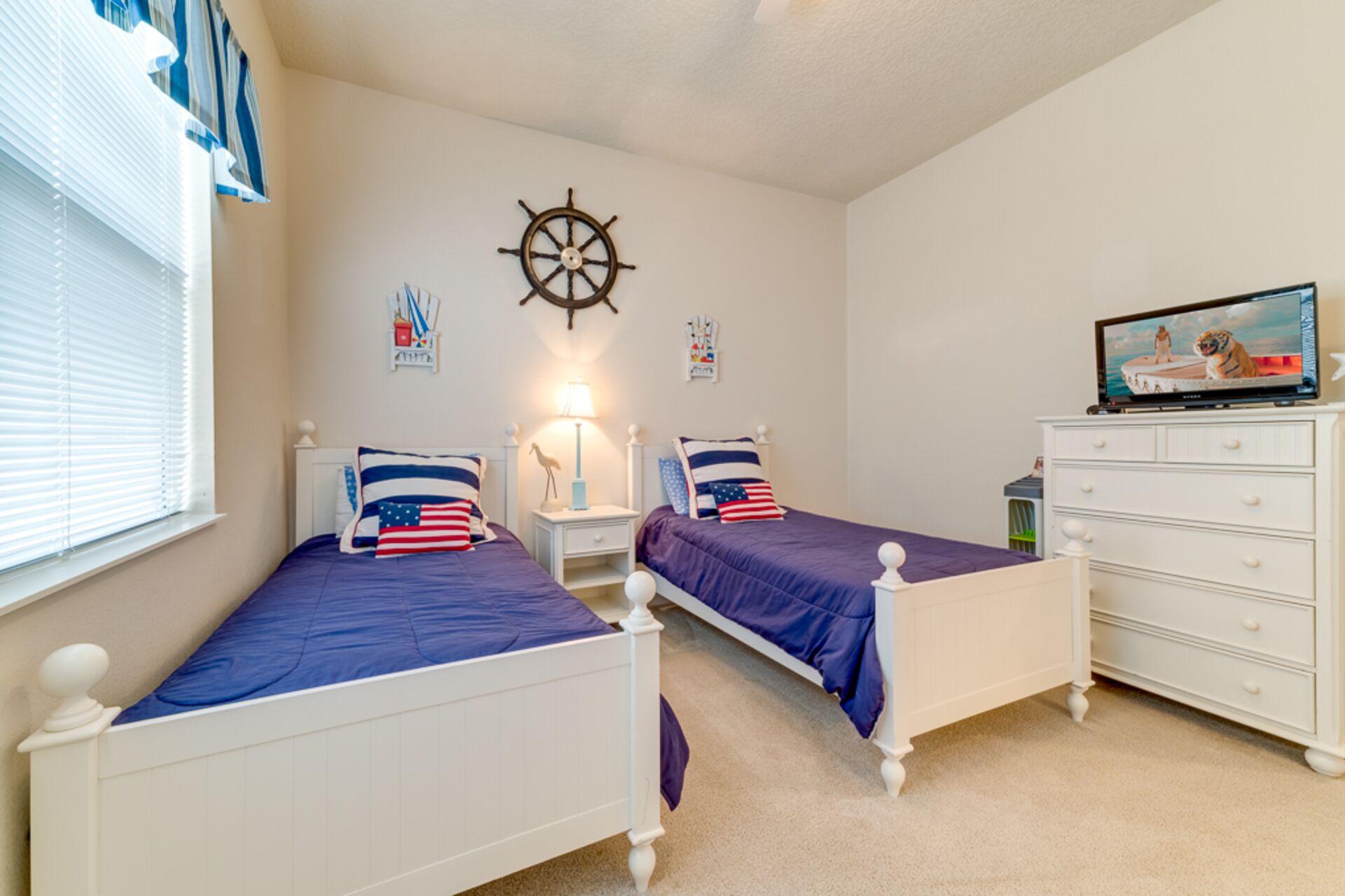 A bedroom with two white beds, a wall clock, a TV, and a dresser.