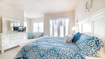 Un dormitorio con una cama grande, un aparador, un televisor y una ventana con cortinas.
