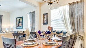 Comedor con una mesa de madera dispuesta para cuatro personas, rodeado de sillas.