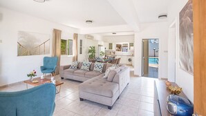 A spacious living room with a sofa set, a dining area, and a kitchen in the background. - Luxury Villa in Cyprus near Beach, Protaras Villa 1267 (Paralimni)