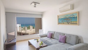 En moderne stue med en grå sofa, et sofabord og et maleri af et kystlandskab.