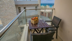 En balkon med fletstole, et træbord og en frugtkurv.