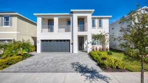 A modern two-story house with a garage, surrounded by well-maintained landscaping and a clear blue sky. - Villa in Encore Resort at Reunion 2979 (Kissimmee)